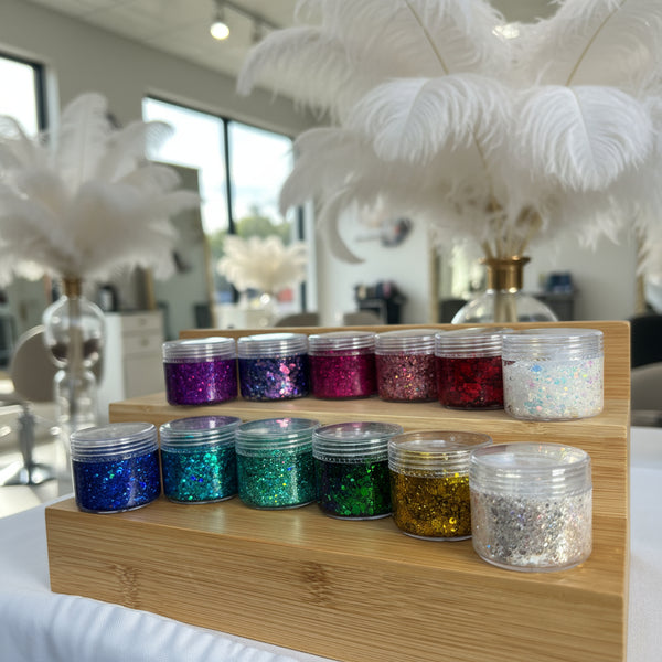 Set of glittery containers on a wooden surface in Glamorous Hair Salon with ostrich feathers