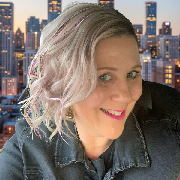 Woman with light-colored hair and denim jacket against a cityscape background