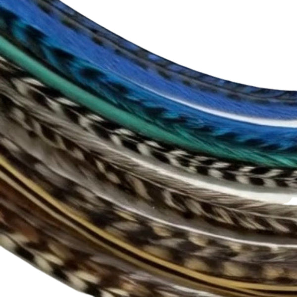 Close-up of blue, green, earthy naturals and black grizzly hair feathers on a white background