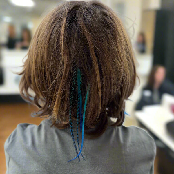 Person with a short haircut and blue hair extensions in an indoor setting