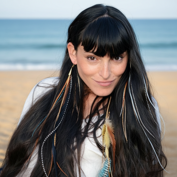 Woman with long black hair featuring colorful feather extensions, wearing a white top.