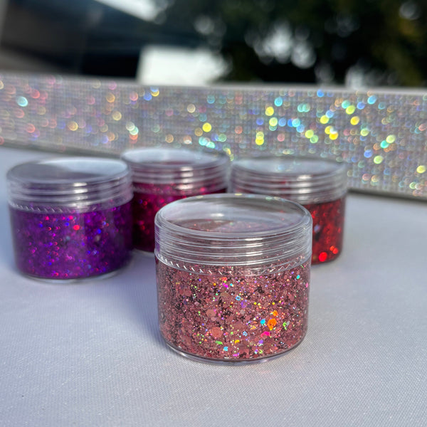 Three small jars of glitter in different colors on a white surface.