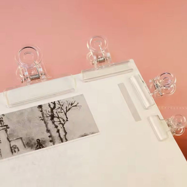 Clear plastic clips on a white board with a pink background