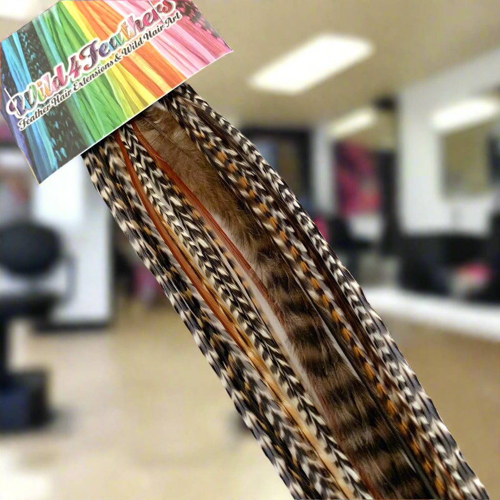 A bundle of feather hair extensions with a mix of brown, black, and white colors, attached to a hair plier.