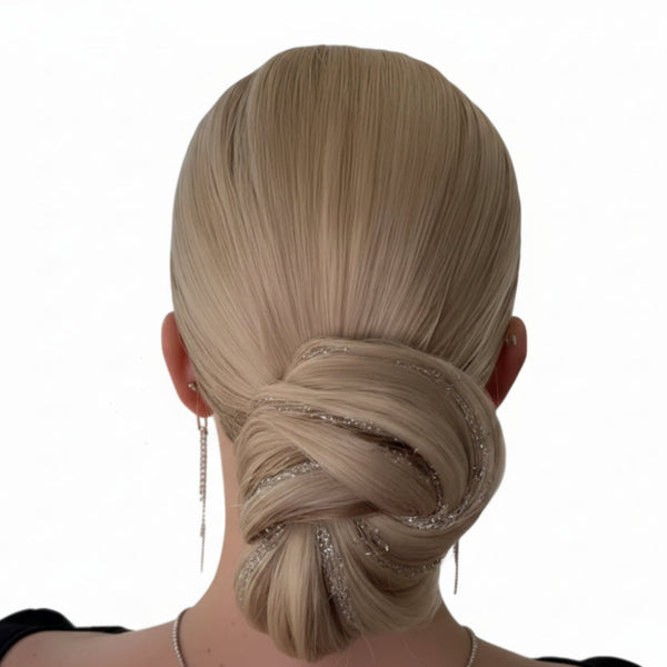Blonde hair styled in an elegant updo with decorative fine hologram silver glitter on a white background