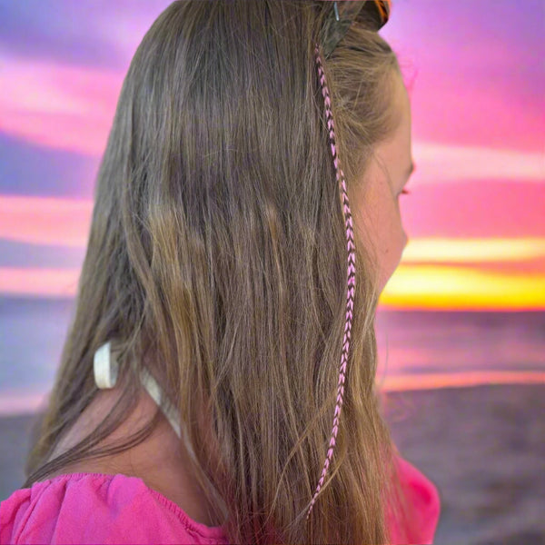 Person with braided hair in a pink headband, blurred background