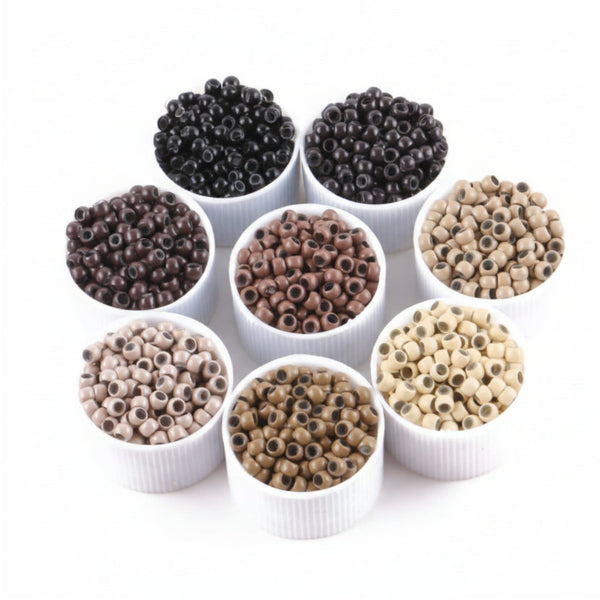 Assorted coloured beads for hair extensions in white containers on a white background