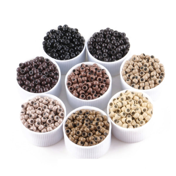 Assorted small beads in white containers on a white background