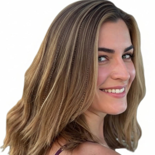 Woman with shoulder-length blonde hair smiling outdoors with fawn feather extensions in hair