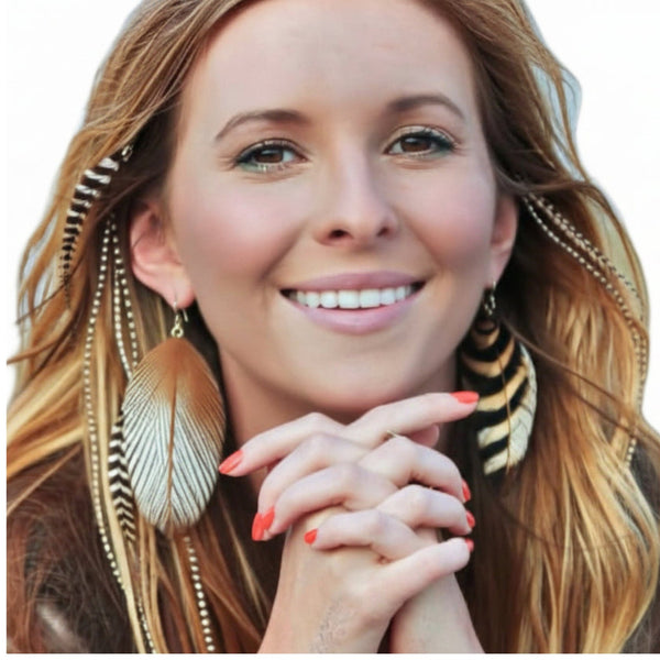 Woman wearing feather hair extensions with feather earrings on a white background