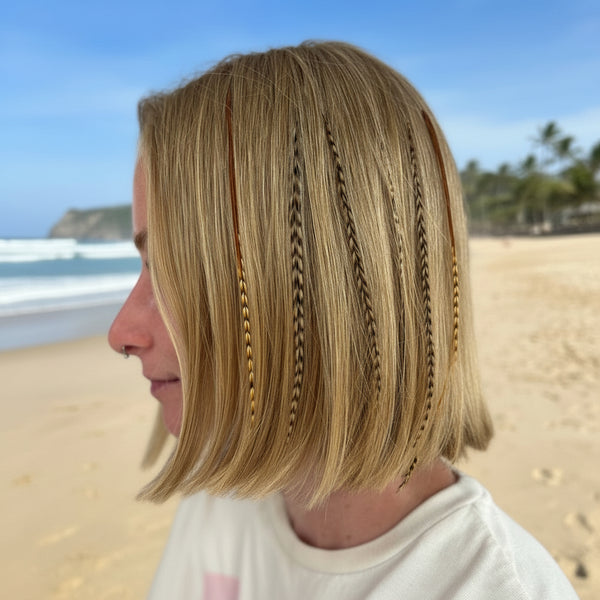 Person with blonde hair styled in Hair Feathers, wearing a white top.