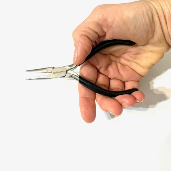 Hand holding a pair of small pliers with black handles on a white background