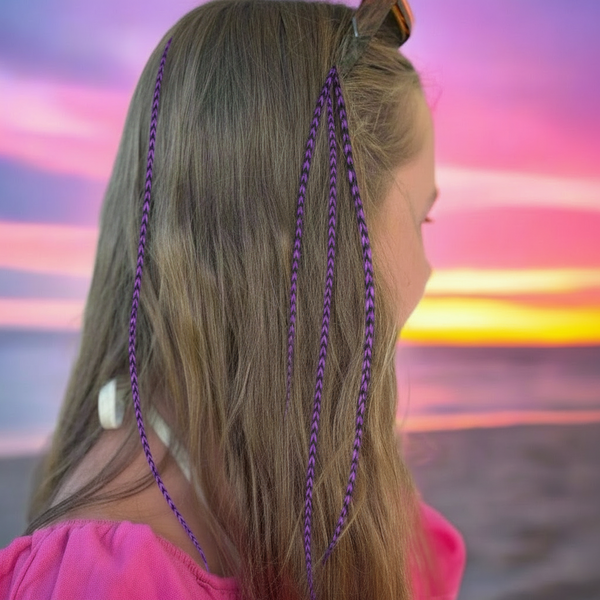 Person with skinny feather extensions in hair against a colorful sunset background