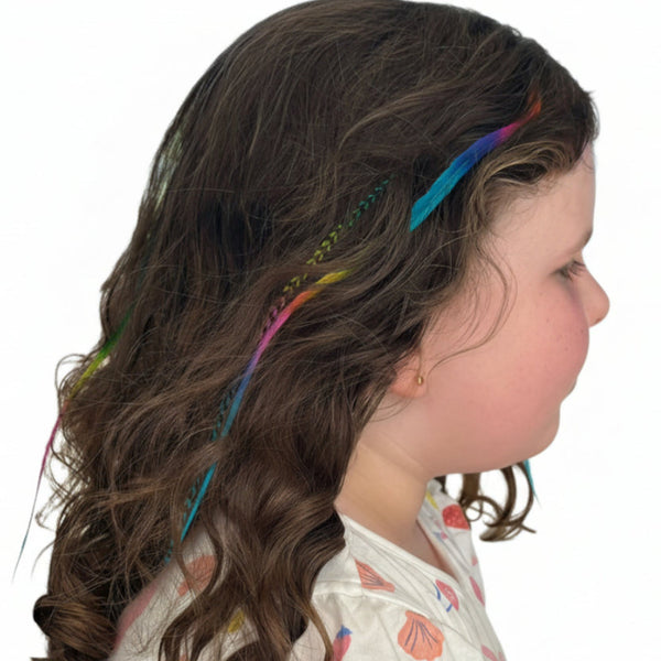 Girl with colourful rainbow feather hair extension accessories in a wavy hairstyle, outdoors.