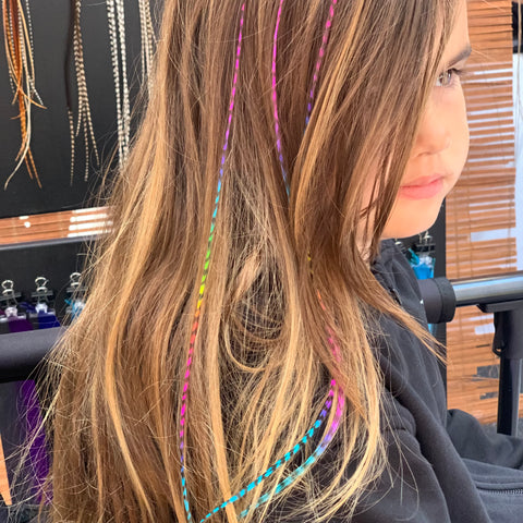 Person with colorful hair extensions in a salon setting