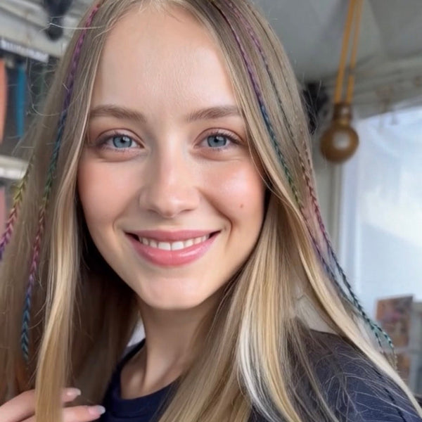 Woman with long blonde hair featuring colorful strands, indoors.