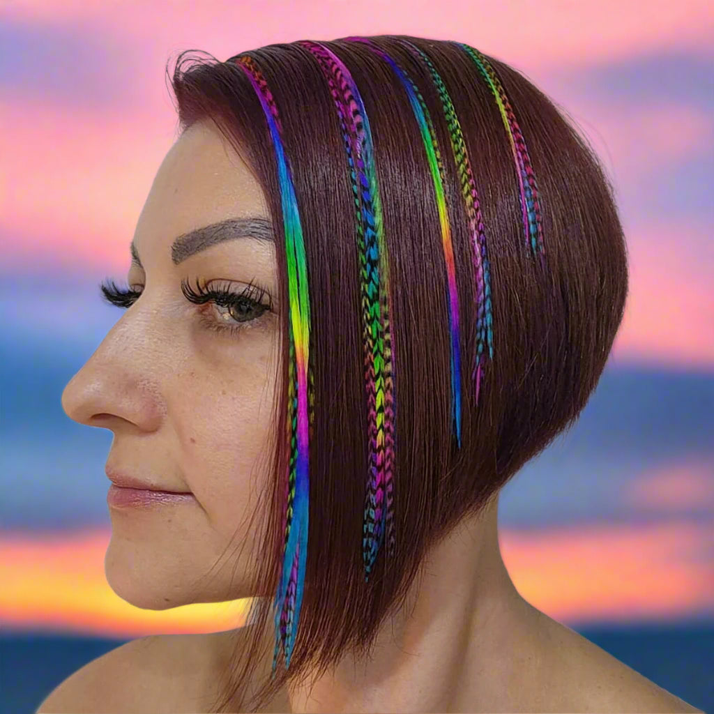 Woman with short brown hair featuring colorful rainbow feather hair extensions in solid and grizzly rainbow feathers against a white background