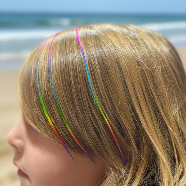 Close-up of a person with rainbow hair extensions.