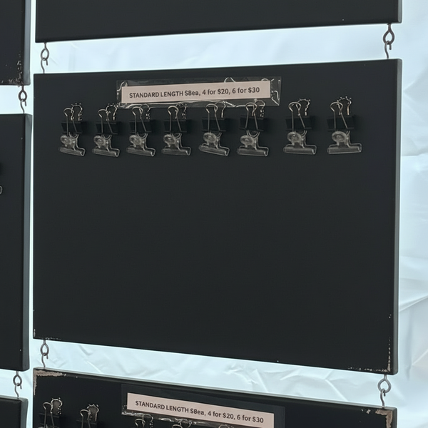 Colorful braided hair extensions hanging on a display board with pricing information.