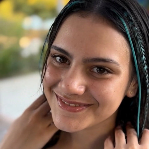 Woman with blue hair feathers smiling outdoors