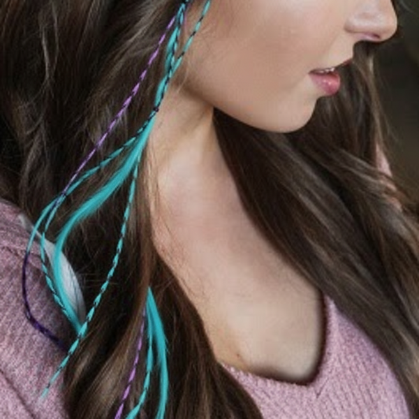 Close-up of a person with colorful hair extensions in a pink sweater.