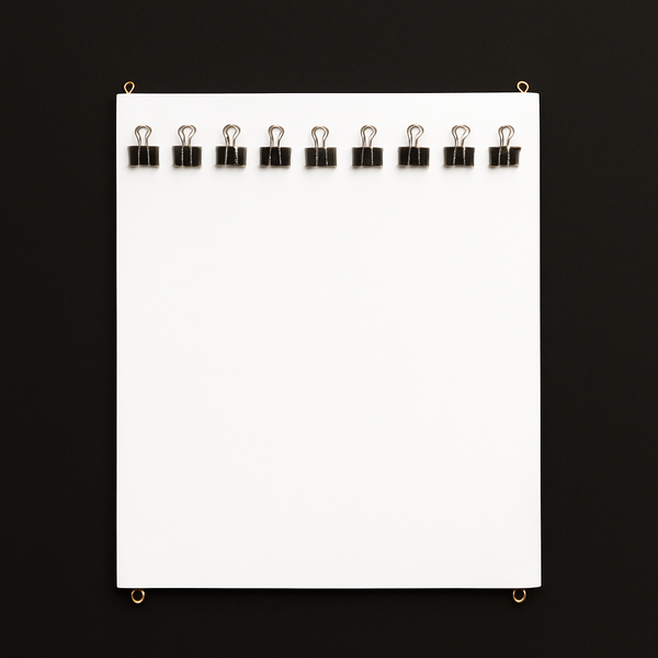 White canvas board with black clips on a black background