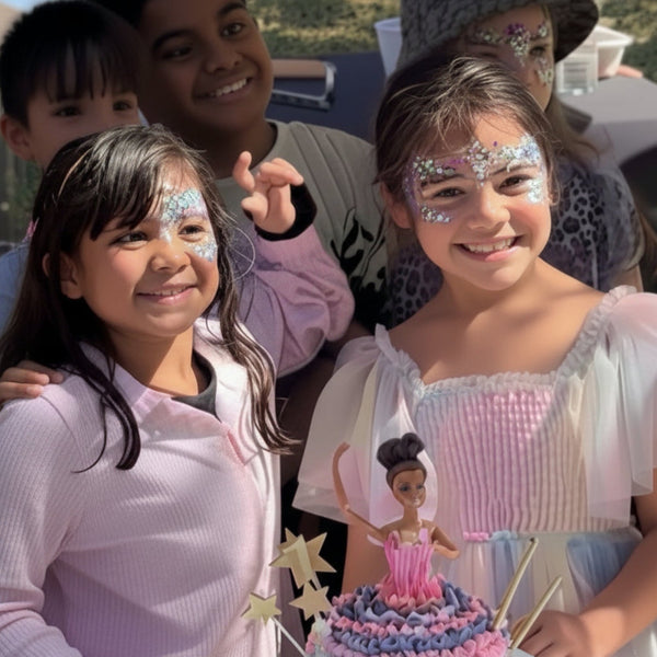 Children with glitter face paint and a decorated birthday cake at an outdoor  wild4feathers party event