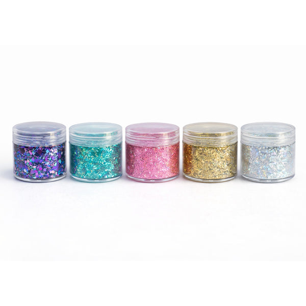 Five jars of glitter in different colors on a white background