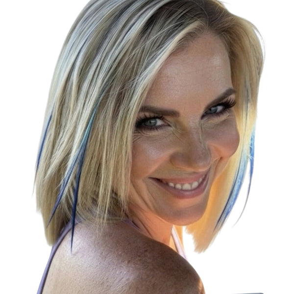 Woman with blonde hair , blue skinny hair feathers, smiling outdoors at beach