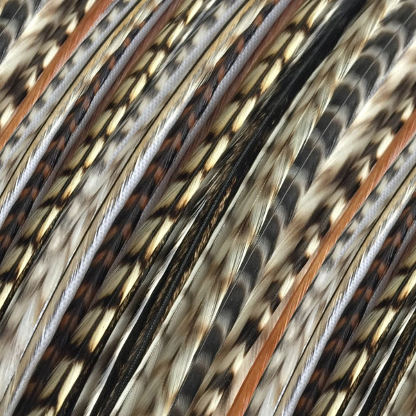 close up of natural varieties of feather hair extensions in regular width of natural fawn grizzly, brown grizzly, black and white grizzly, chocolate grizzly varieties, and blonde grizzly  varieties, of real striped feathers for hairstyling