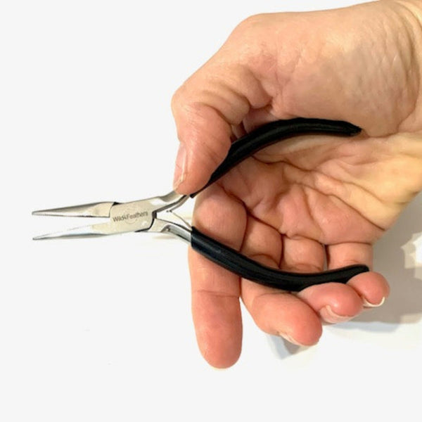Hand holding a pair of hair extension pliers for attaching hair extensions