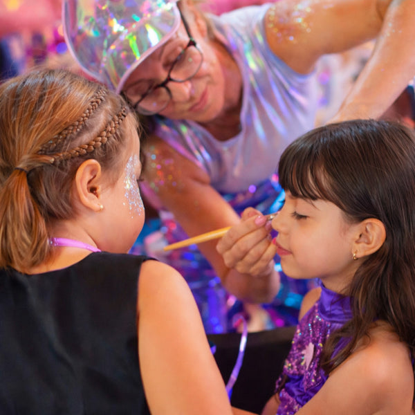 wild4feathers staff member applying glitter glam face paint to a child at a disco on sunshine coast QLD
