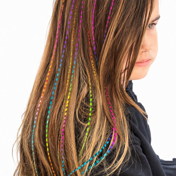 female wearing long rainbow grizzly feather hair extensions in long brown hair