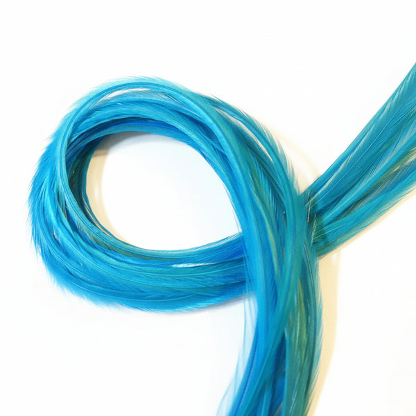 A bundle of turquoise solid feather hair extensions laid out on a surface.